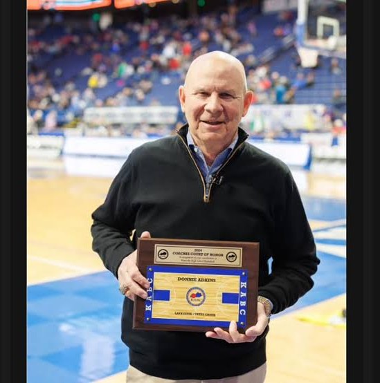 Coach Don Adkins holding his Kentucky Association of Basketball Coaches Coaches Court of Honor plaque on a basketball court